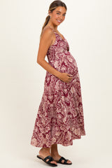 woman wearing a burgundy floral maternity dress with a tiered skirt and holding her baby bump
