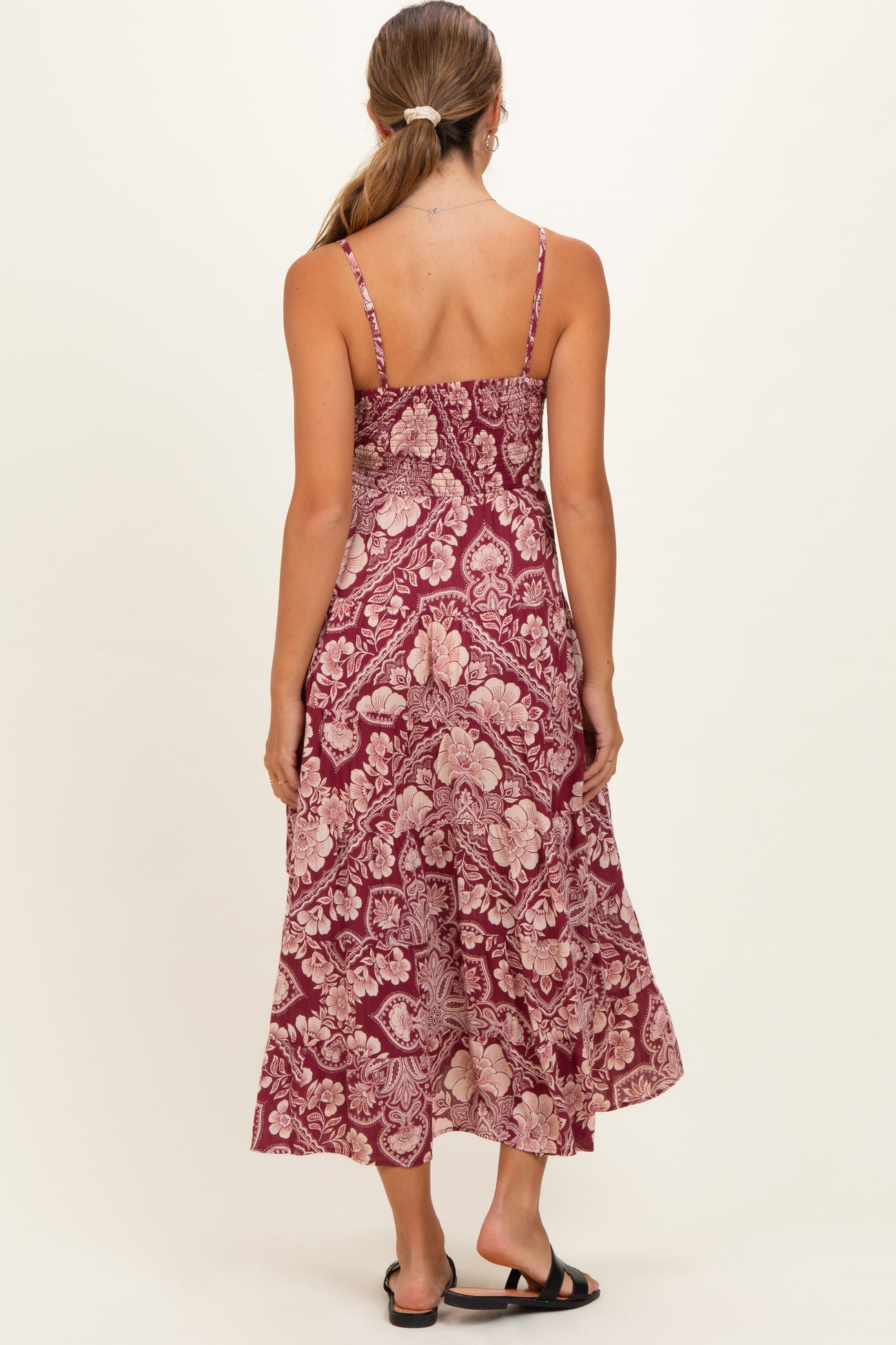 woman wearing a maroon floral maternity maxi dress with thin straps and a flowy silhouette