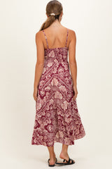 woman wearing a maroon floral maternity maxi dress with thin straps and a flowy silhouette
