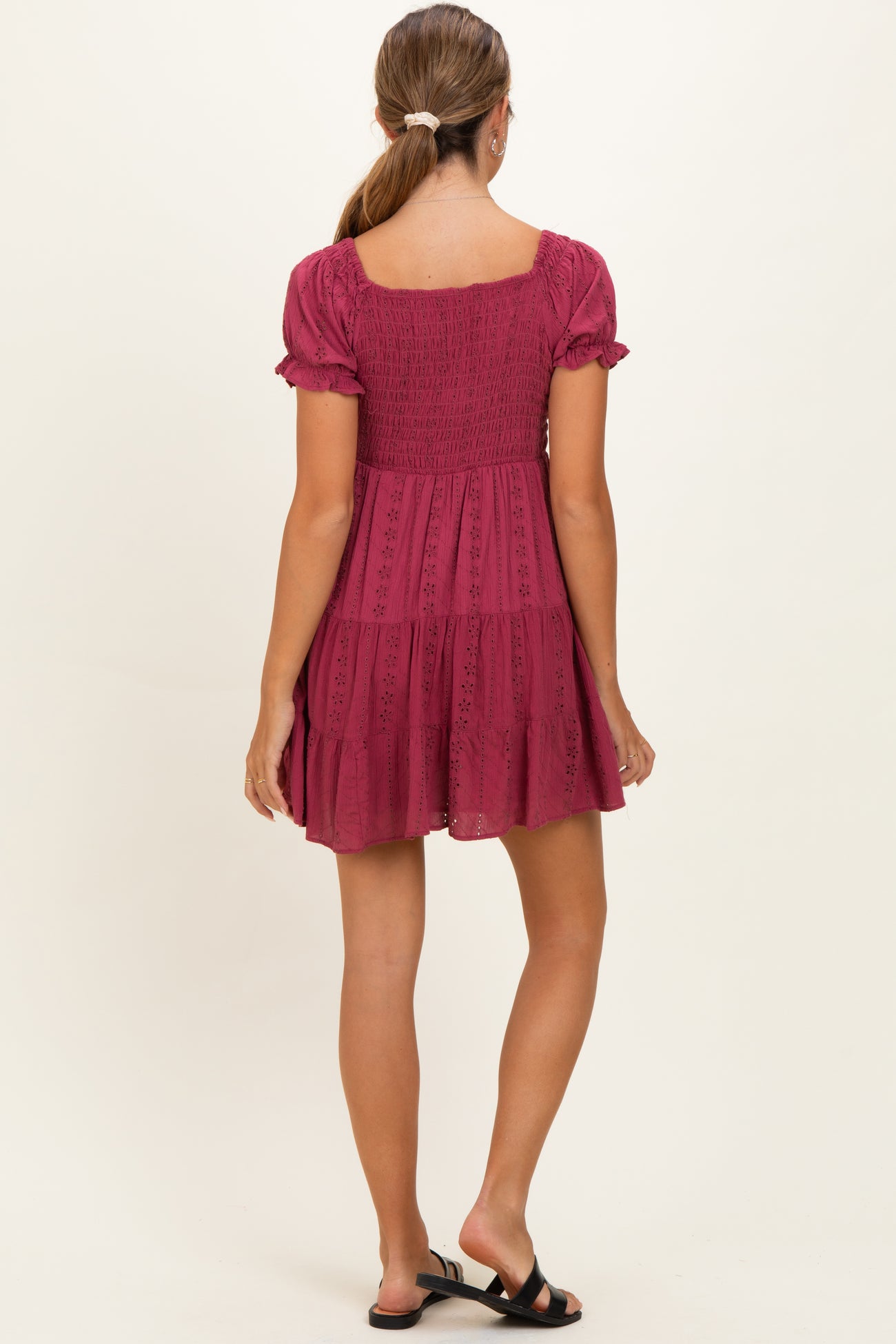 woman wearing a dark pink maternity dress with short puff sleeves and a tiered skirt, showing a relaxed fit from the back