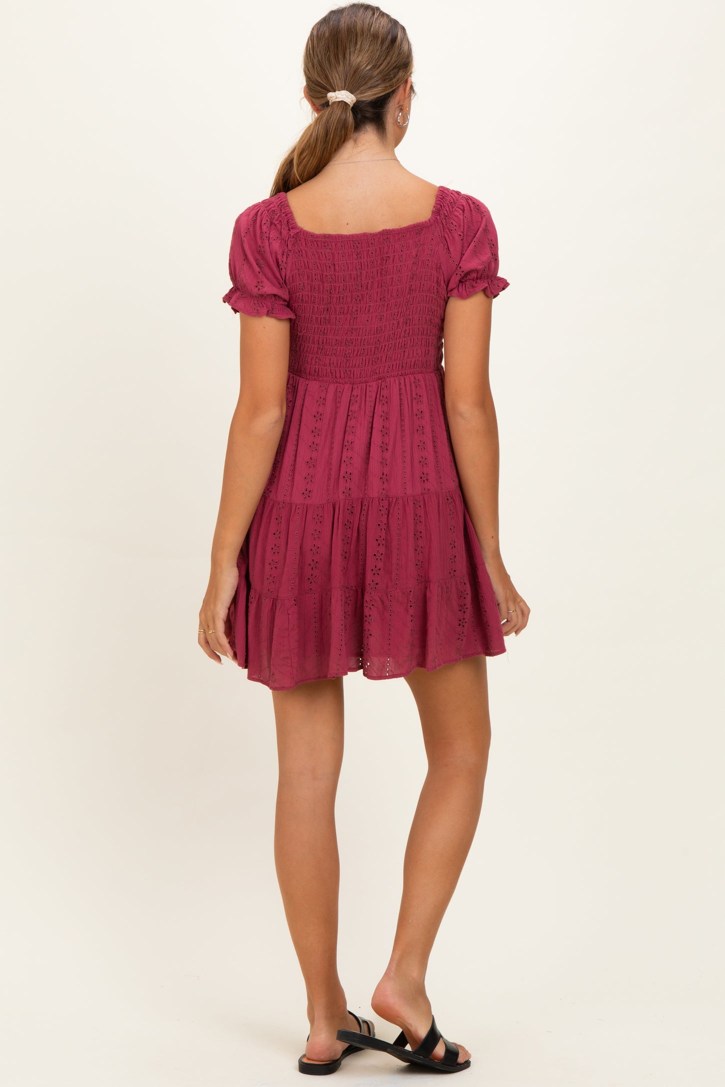 woman wearing a dark pink maternity dress with short puff sleeves and a tiered skirt, showing a relaxed fit from the back