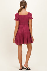 woman wearing a dark pink maternity dress with short puff sleeves and a tiered skirt, showing a relaxed fit from the back