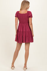 woman wearing a burgundy short sleeve tiered sundress with a smocked bodice and floral details