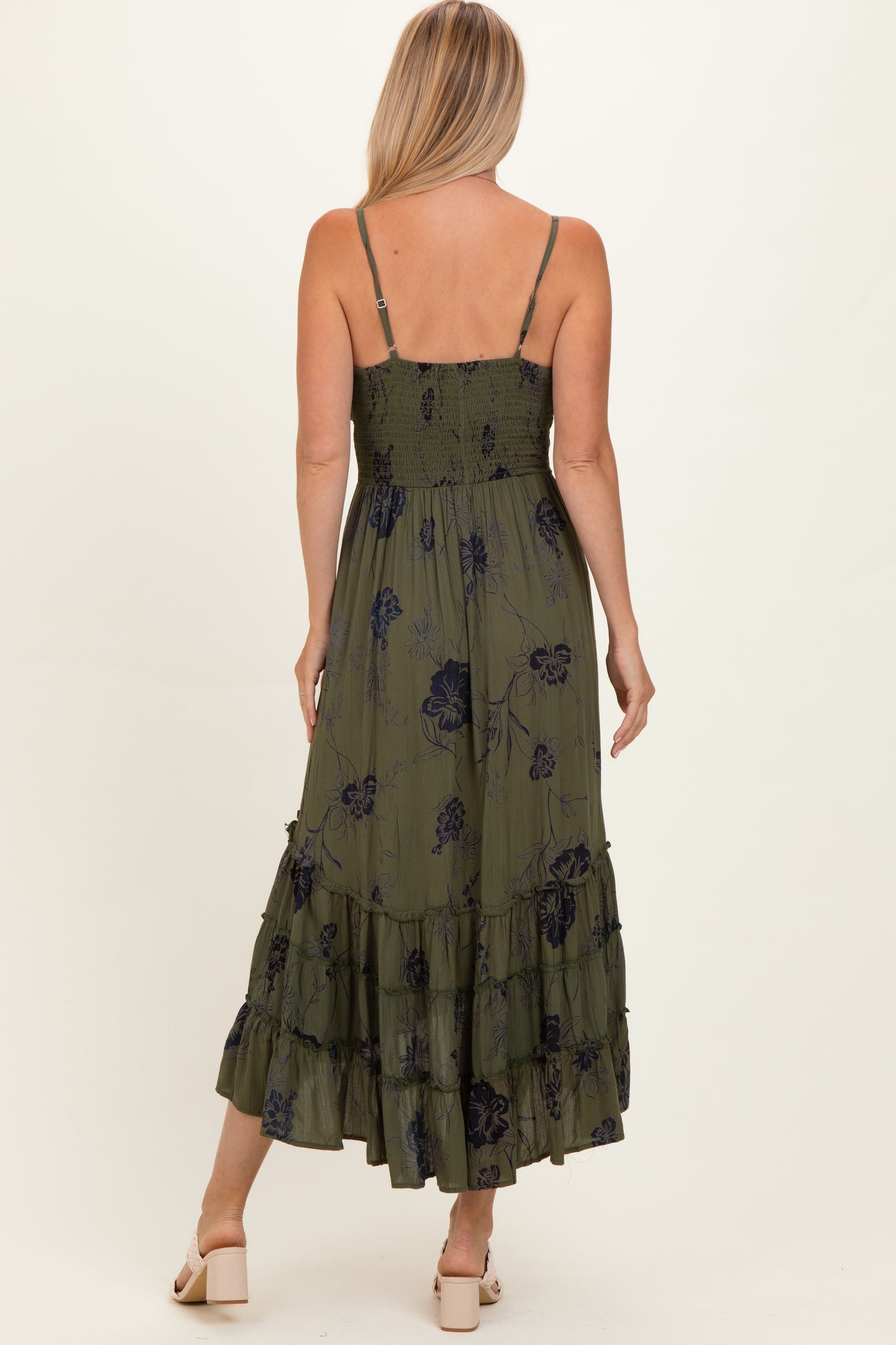woman wearing an olive green floral maxi dress with ruffled layers and adjustable spaghetti straps, seen from the back
