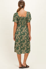 woman wearing a green floral maternity dress with short sleeves, showing the back view and gathered detailing