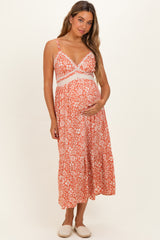 woman wearing an orange floral print maternity dress with lace details, highlighting her baby bump