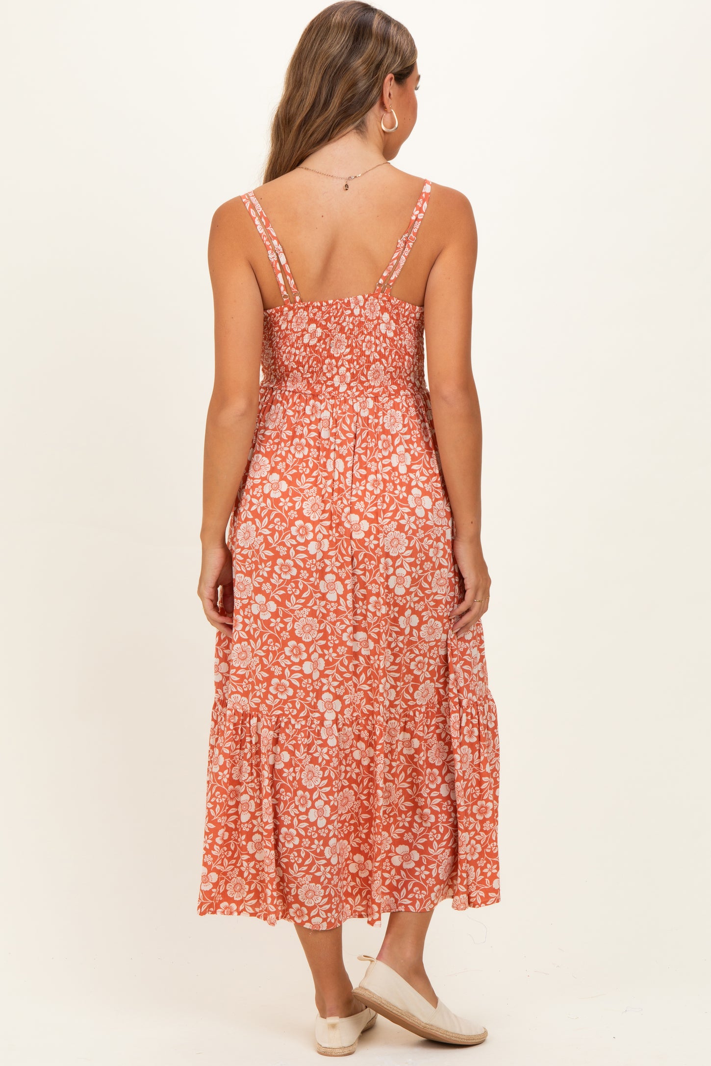 woman wearing a flowy orange floral maternity maxi dress, shown from the back