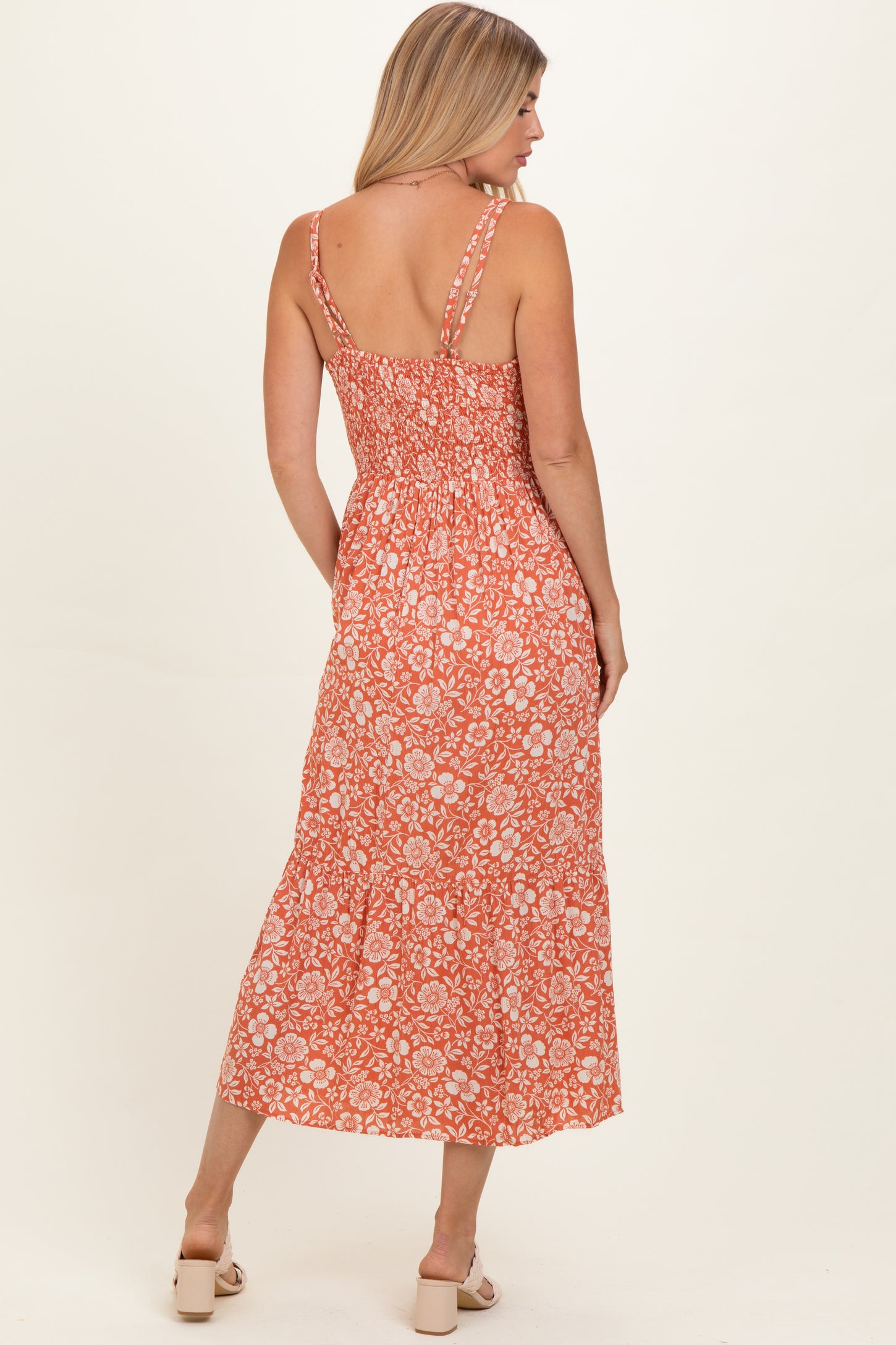 woman wearing an orange floral maxi dress with a smocked back and adjustable straps
