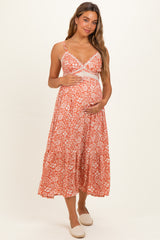 woman wearing an orange floral maternity maxi dress and holding her baby bump
