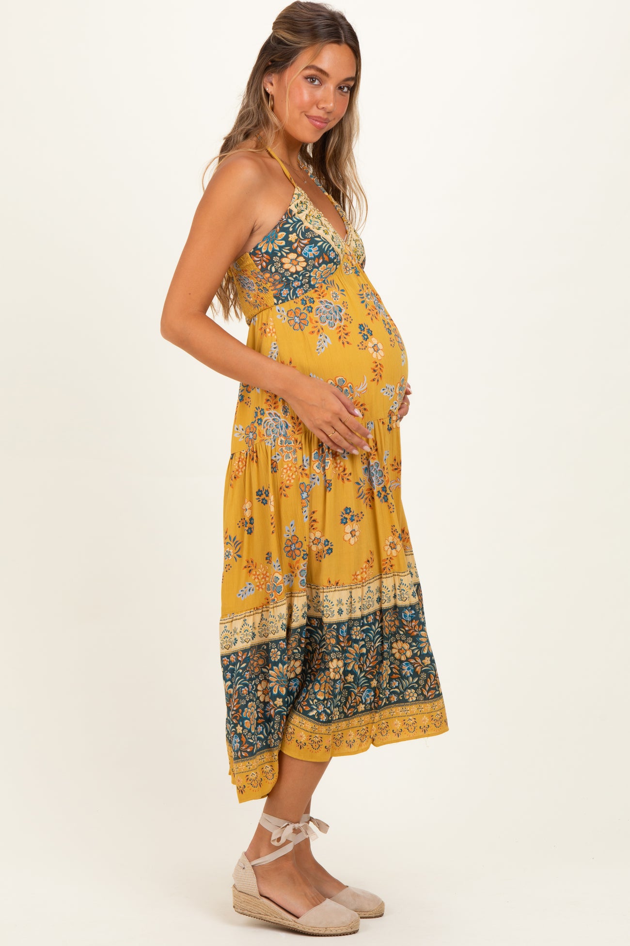 woman wearing a yellow floral maternity maxi dress and holding her baby bump