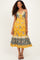 woman wearing a yellow floral halter neck maxi dress with tiered hem and intricate border details