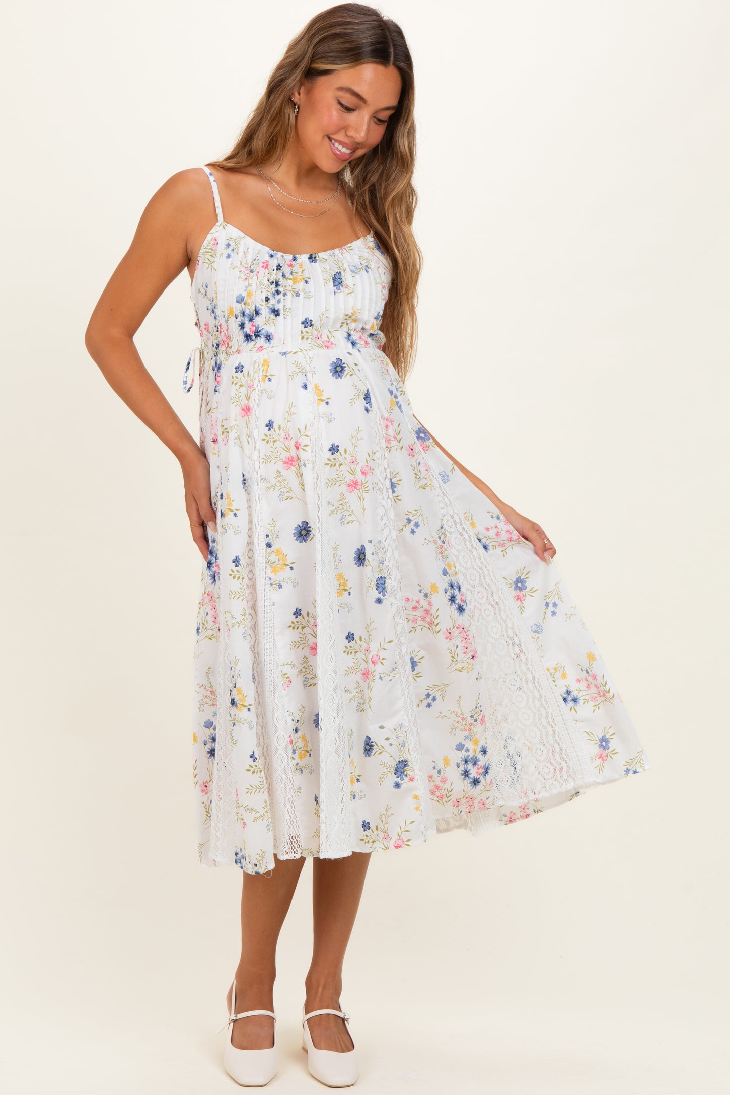 woman wearing a floral print white maternity dress with lace details and a visible baby bump