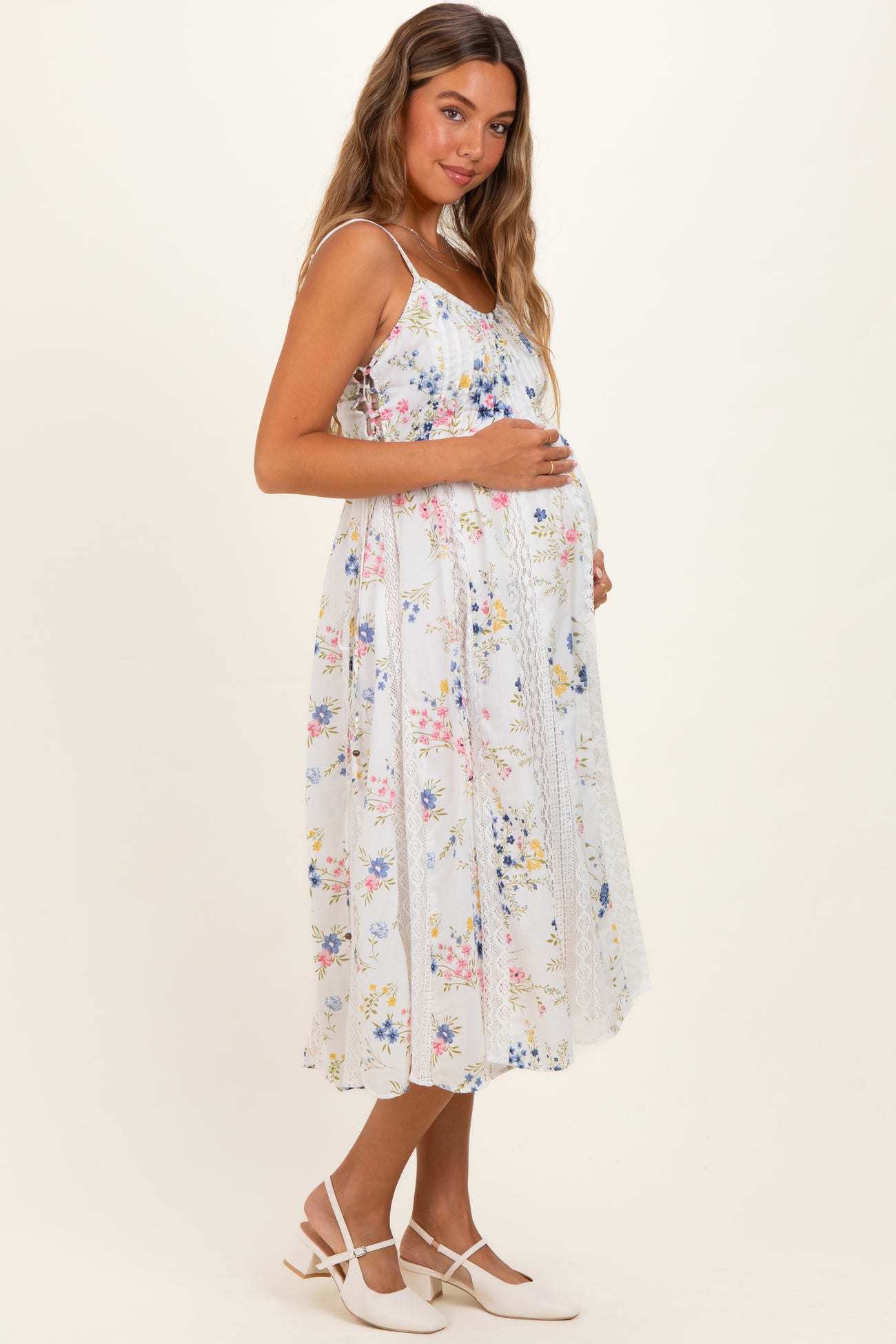 woman wearing a white floral maternity dress with a flowy silhouette and a visible baby bump