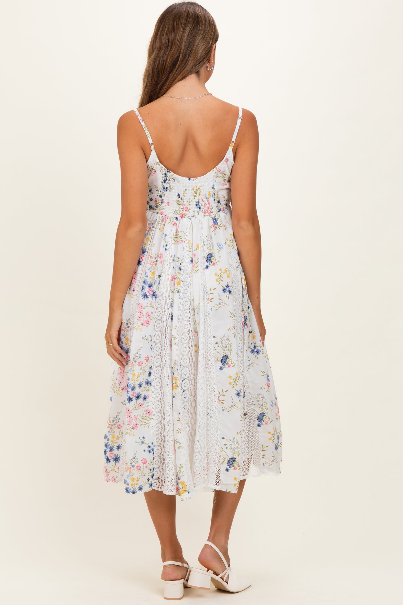 woman wearing a floral print maternity dress with lace detailing and a flowing skirt, viewed from the back