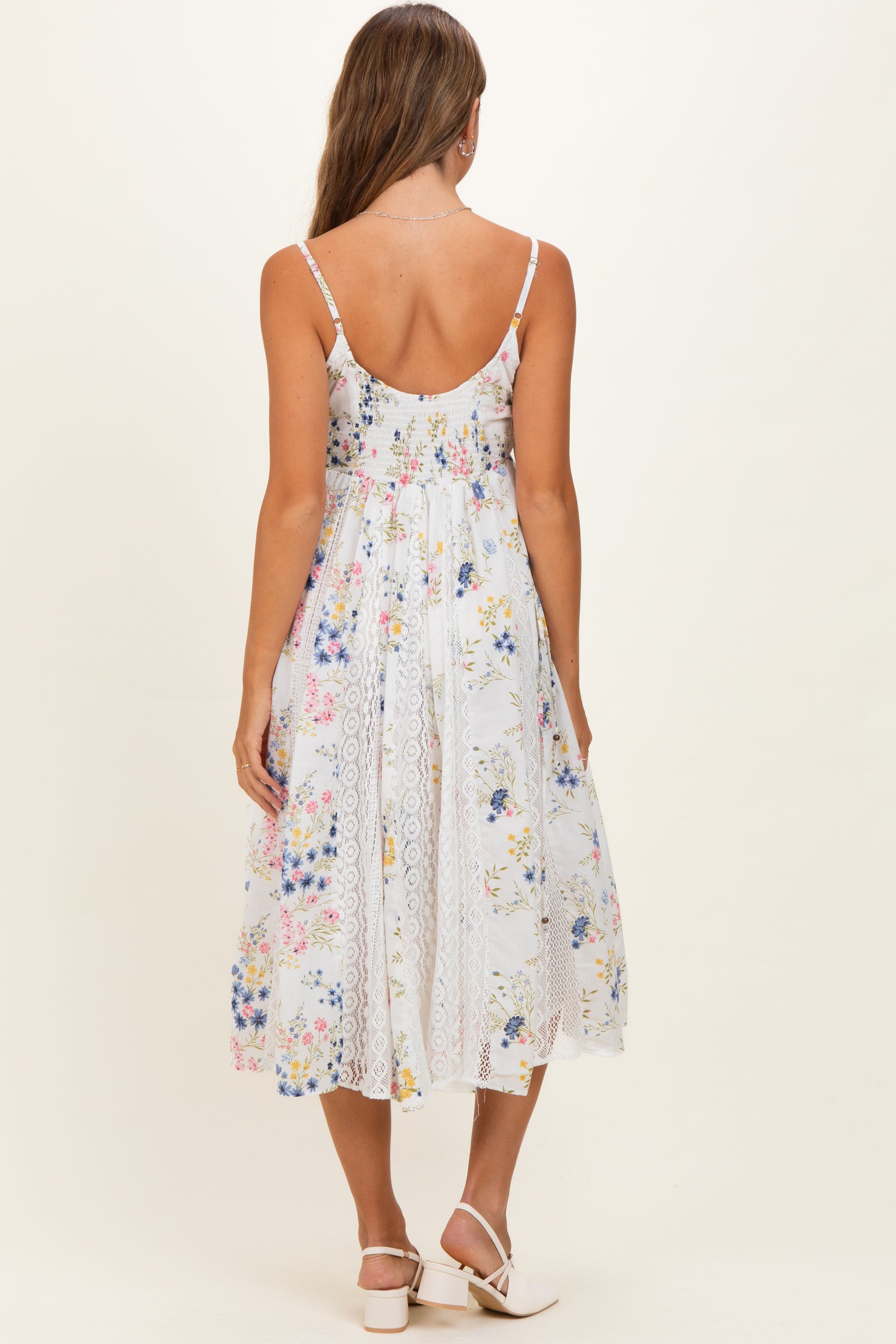 woman wearing a floral print maternity dress with lace detailing and a flowing skirt, viewed from the back