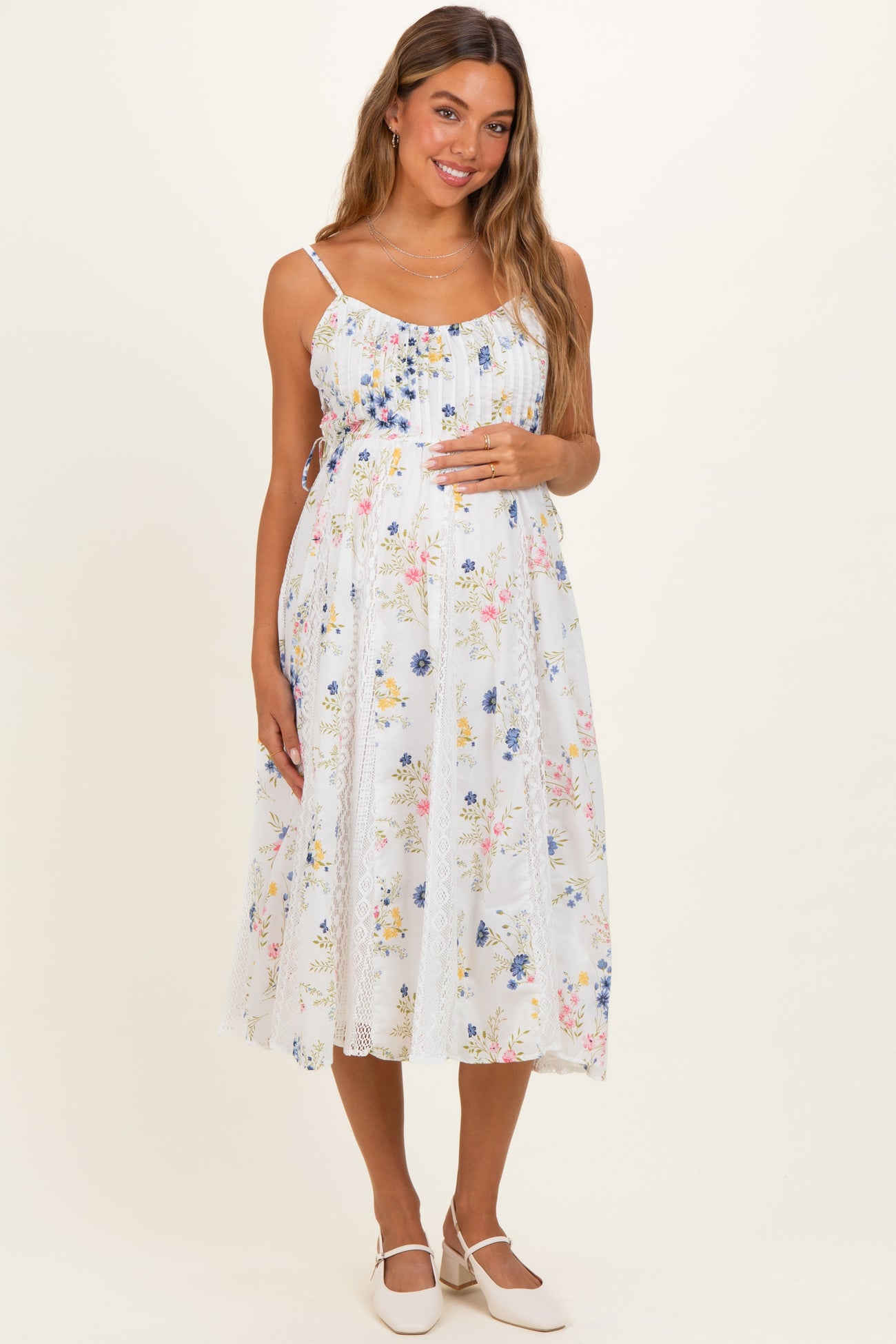 woman wearing a white floral maternity dress with adjustable straps and a visible baby bump