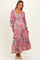 woman wearing a pink floral long sleeve maternity maxi dress with a tiered skirt and a visible baby bump