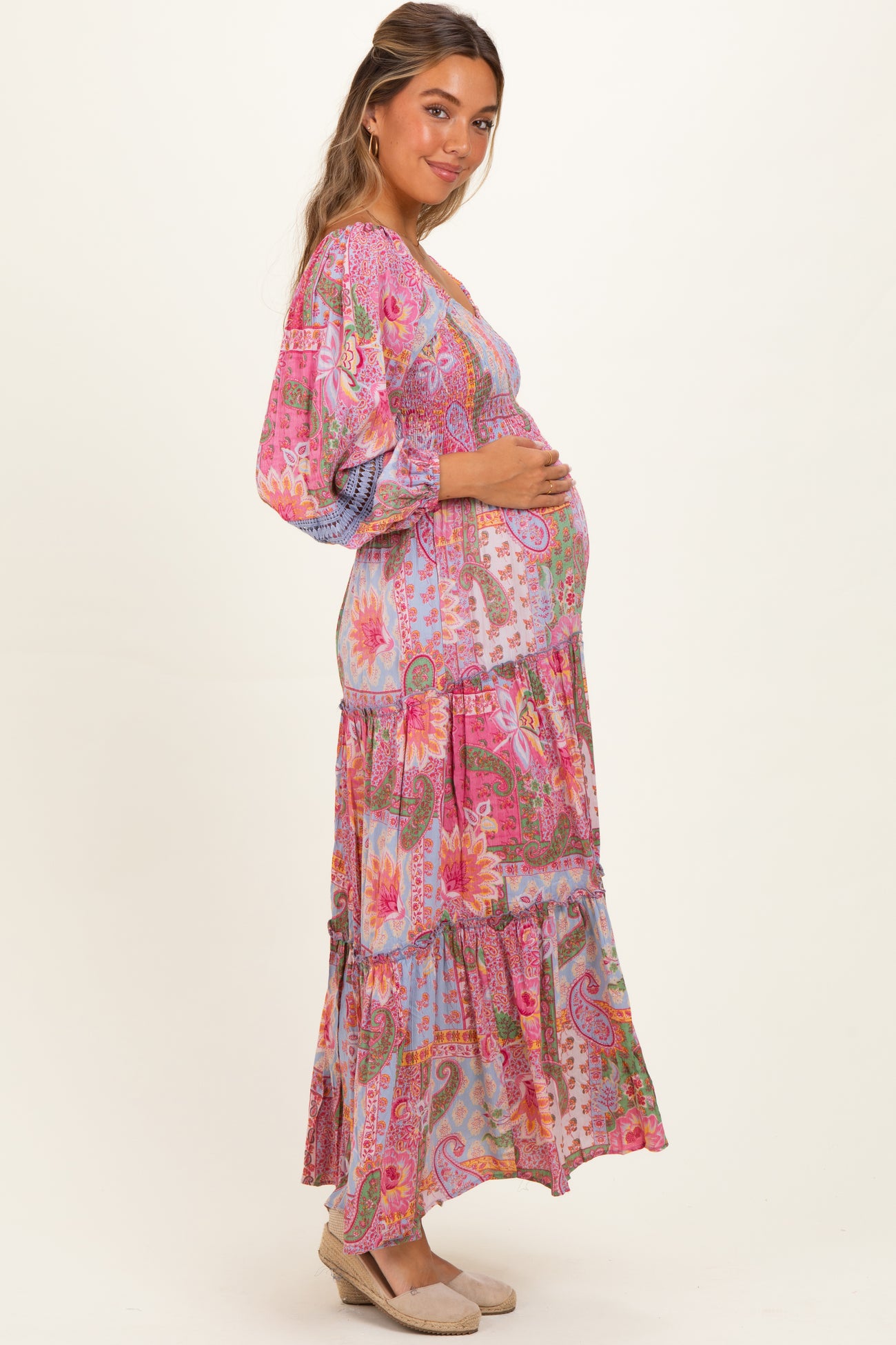 woman wearing a multi-colored floral print maternity maxi dress with a visible baby bump