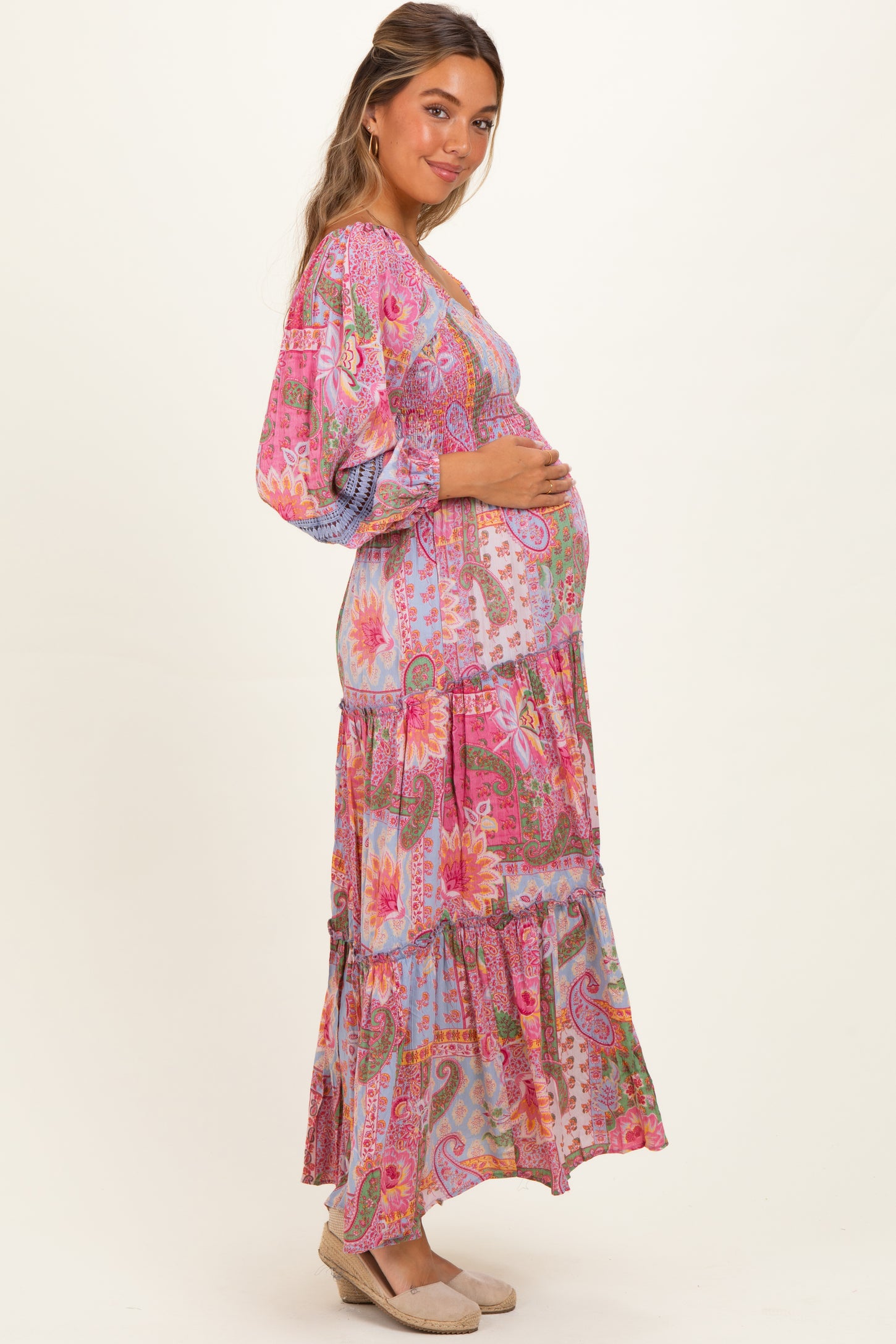 woman wearing a multi-colored floral print maternity maxi dress with a visible baby bump