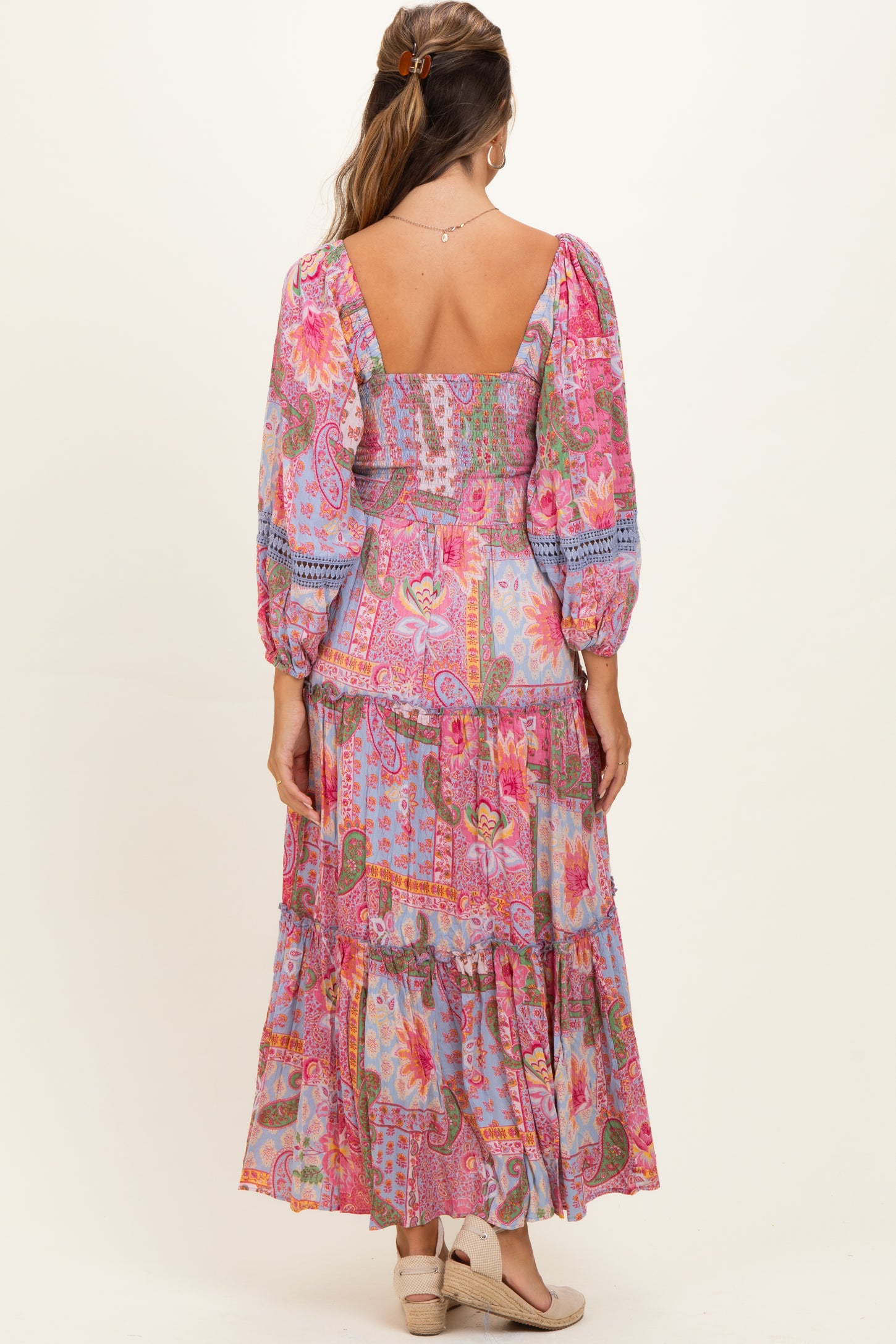 woman wearing a colorful floral maternity maxi dress with puff sleeves and a tiered skirt, showing a baby bump