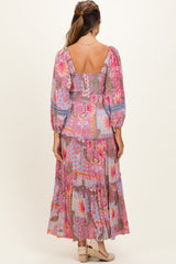 woman wearing a colorful floral maternity maxi dress with puff sleeves and a tiered skirt, showing a baby bump