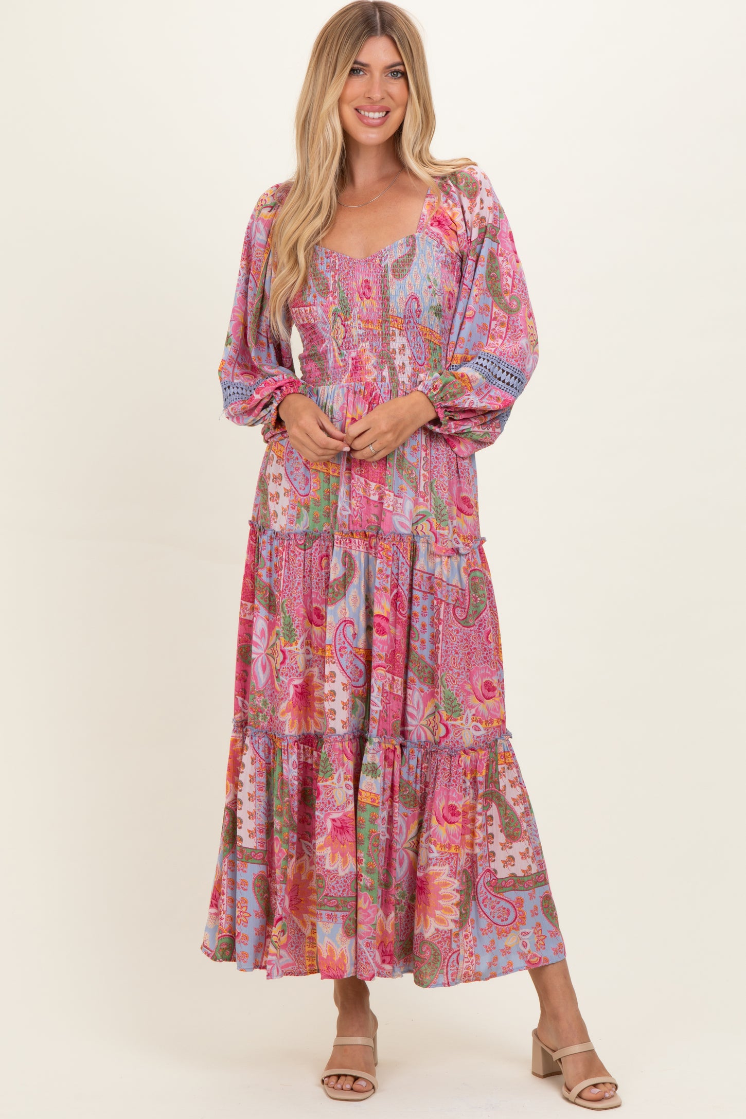 woman wearing a pink and multicolor floral maxi dress with long sleeves and a tiered skirt