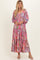 woman wearing a pink and multicolor floral maxi dress with long sleeves and a tiered skirt
