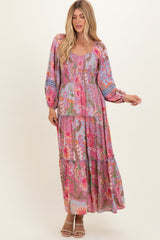 woman wearing a colorful floral maxi dress with long sleeves and a tiered skirt