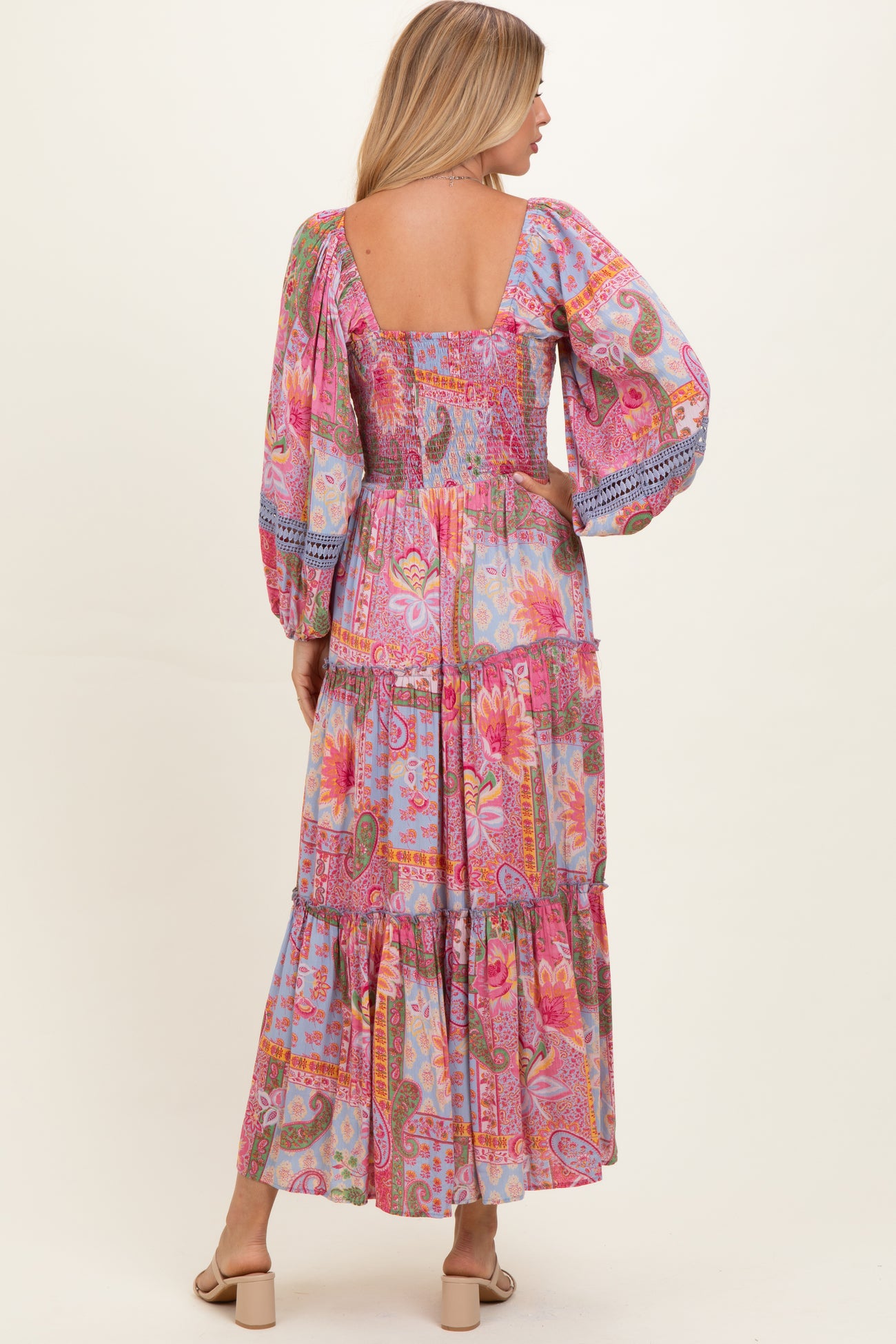 woman wearing a colorful patterned maxi dress with puff sleeves and a tiered skirt, viewed from the back