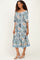 woman wearing a floral print mid-length dress with puff sleeves and a smocked bodice, paired with white strappy sandals