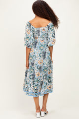 woman wearing a patterned midi dress with puff sleeves and a square back detail, standing with her back to the camera