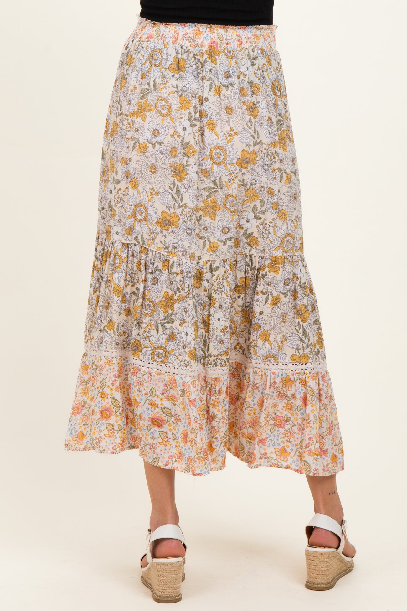 woman wearing a floral print maternity maxi skirt with tiered ruffles in soft colors