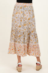 woman wearing a floral print maternity maxi skirt with tiered ruffles in soft colors
