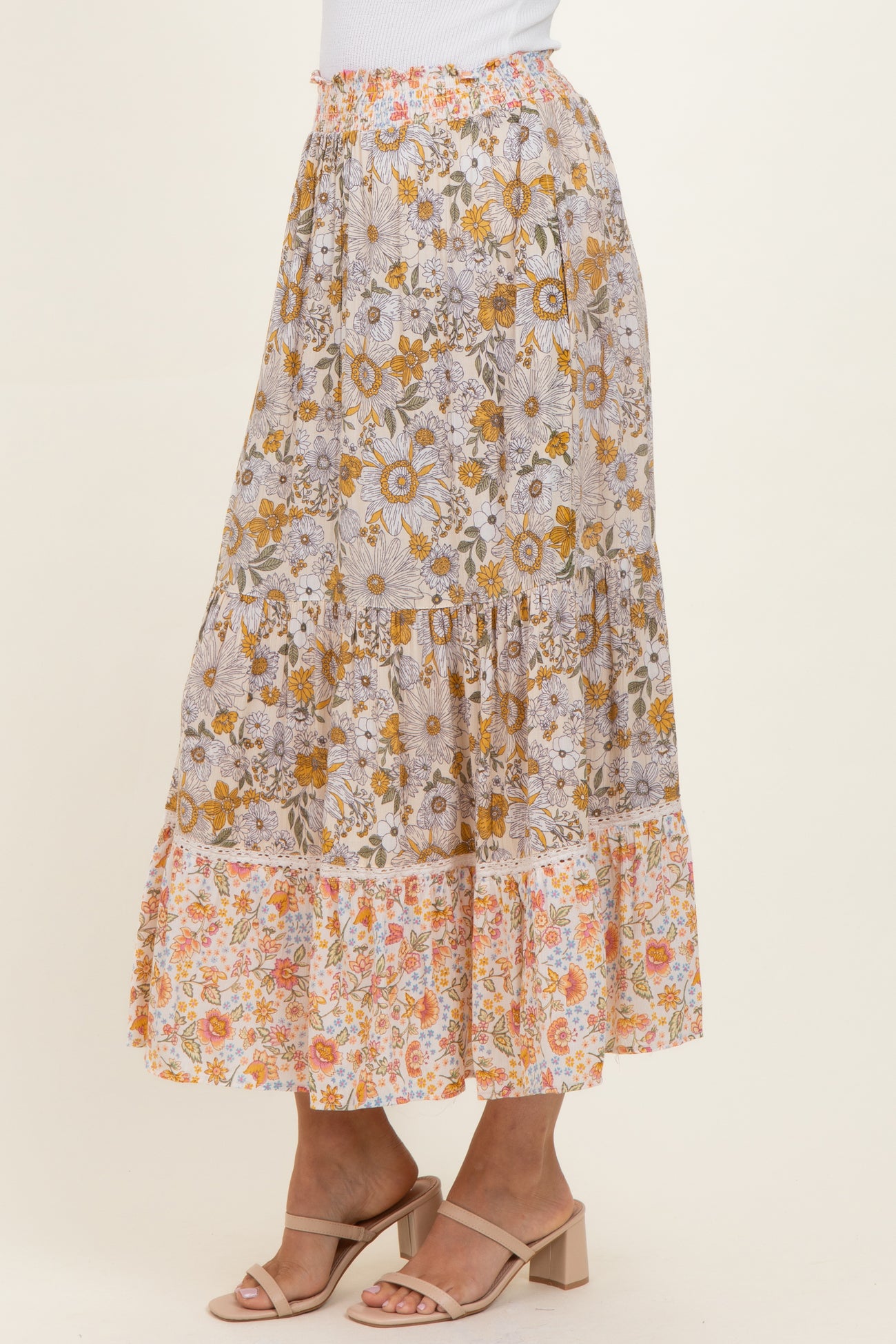 woman wearing a floral print maxi skirt with tiers in shades of yellow, orange, and white