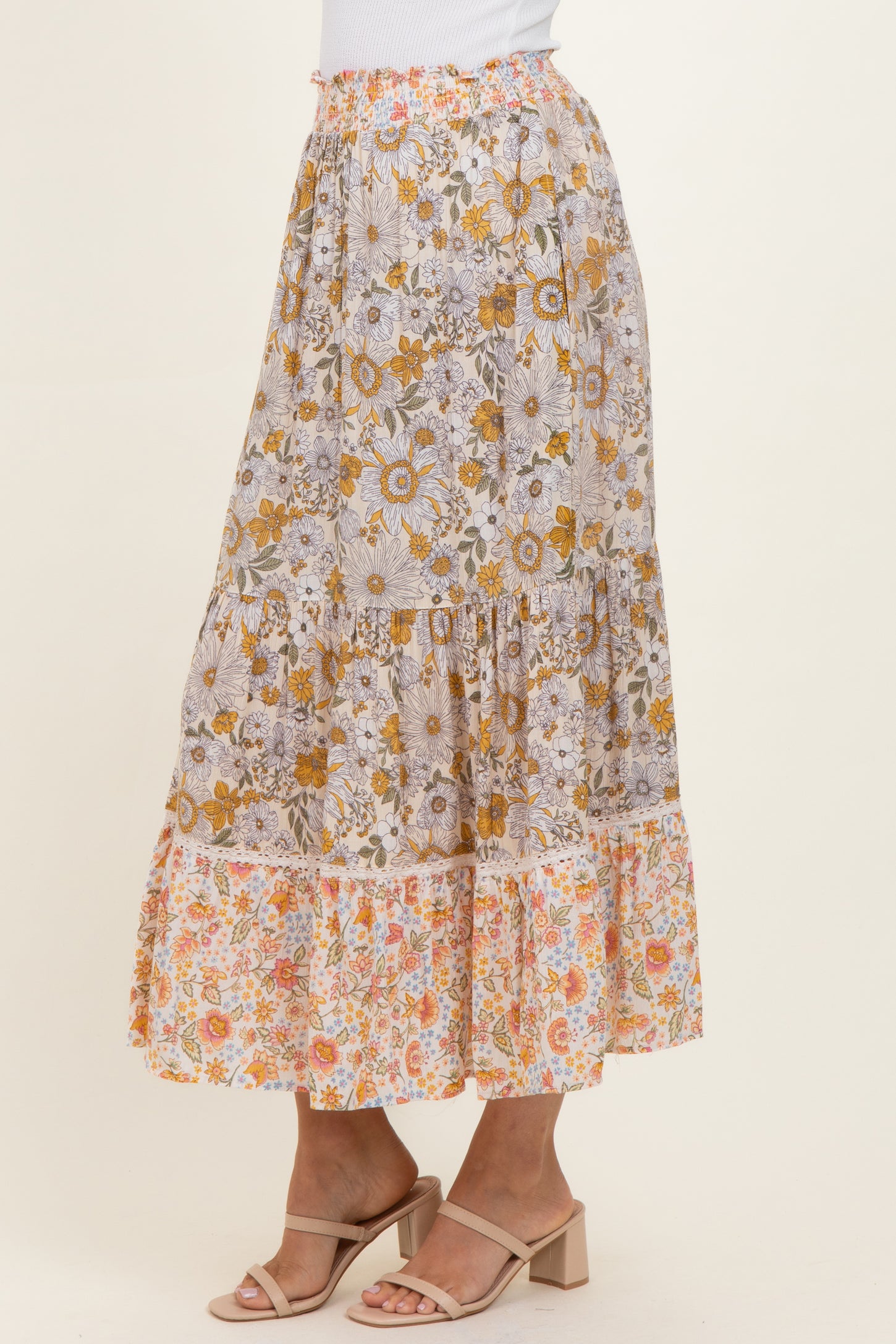 woman wearing a floral print maxi skirt with tiers in shades of yellow, orange, and white
