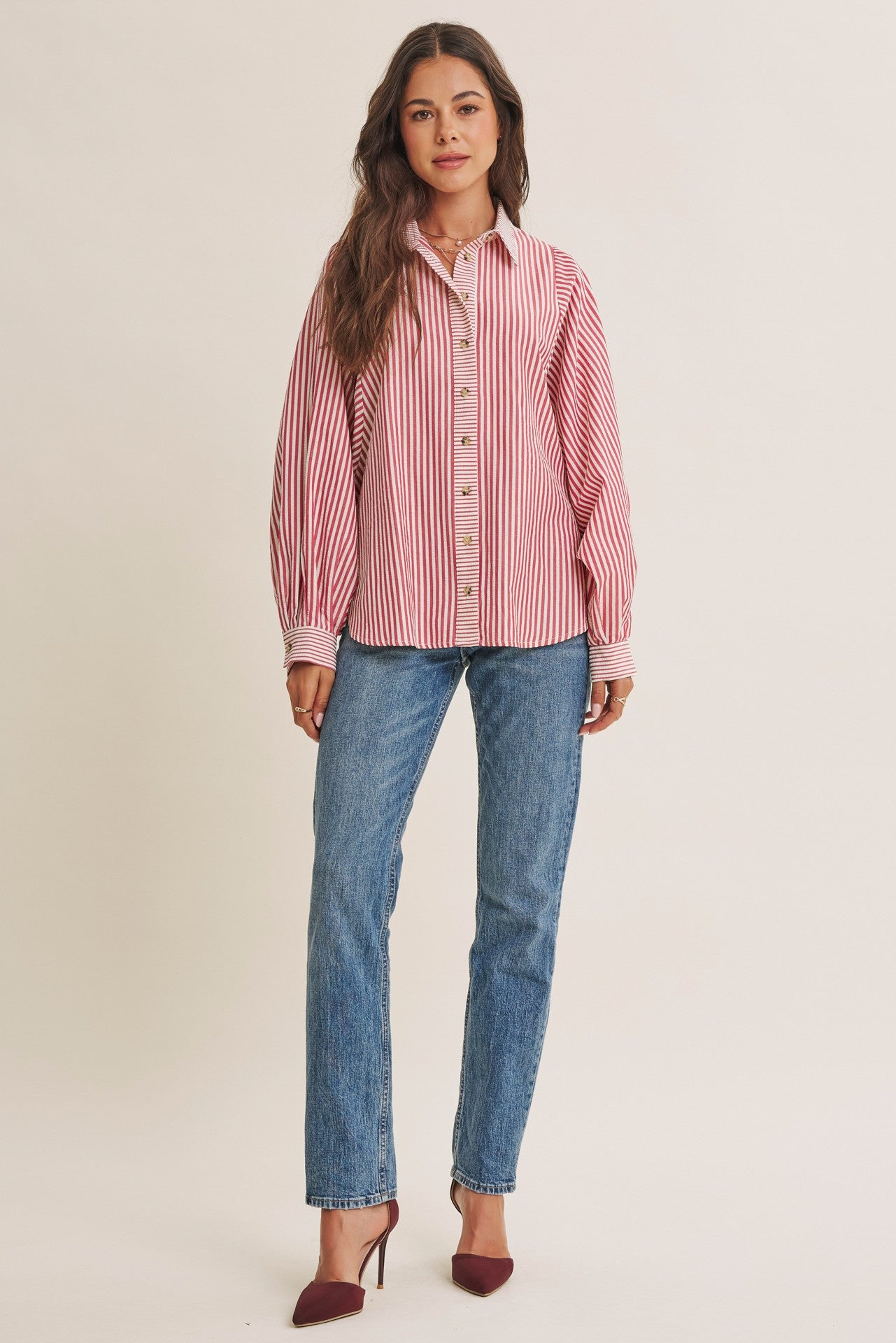 woman wearing a red and white striped button-up shirt with long sleeves and light blue straight leg jeans