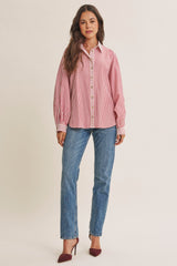 woman wearing a red and white striped button-up shirt with long sleeves and light blue straight leg jeans