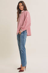 woman wearing a red and white striped oversized button-up shirt with blue jeans and maroon pointed-toe heels