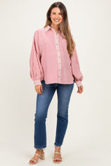 woman wearing a red and white striped maternity shirt with balloon sleeves and blue jeans, smiling at the camera