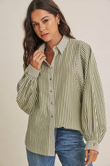 woman wearing a green and white striped oversized button-up shirt with puffed sleeves and paired with blue jeans