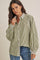 woman wearing a green and white striped oversized button-up shirt with puffed sleeves and paired with blue jeans