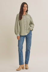 woman wearing a green and white striped oversized button-up shirt with balloon sleeves and blue jeans
