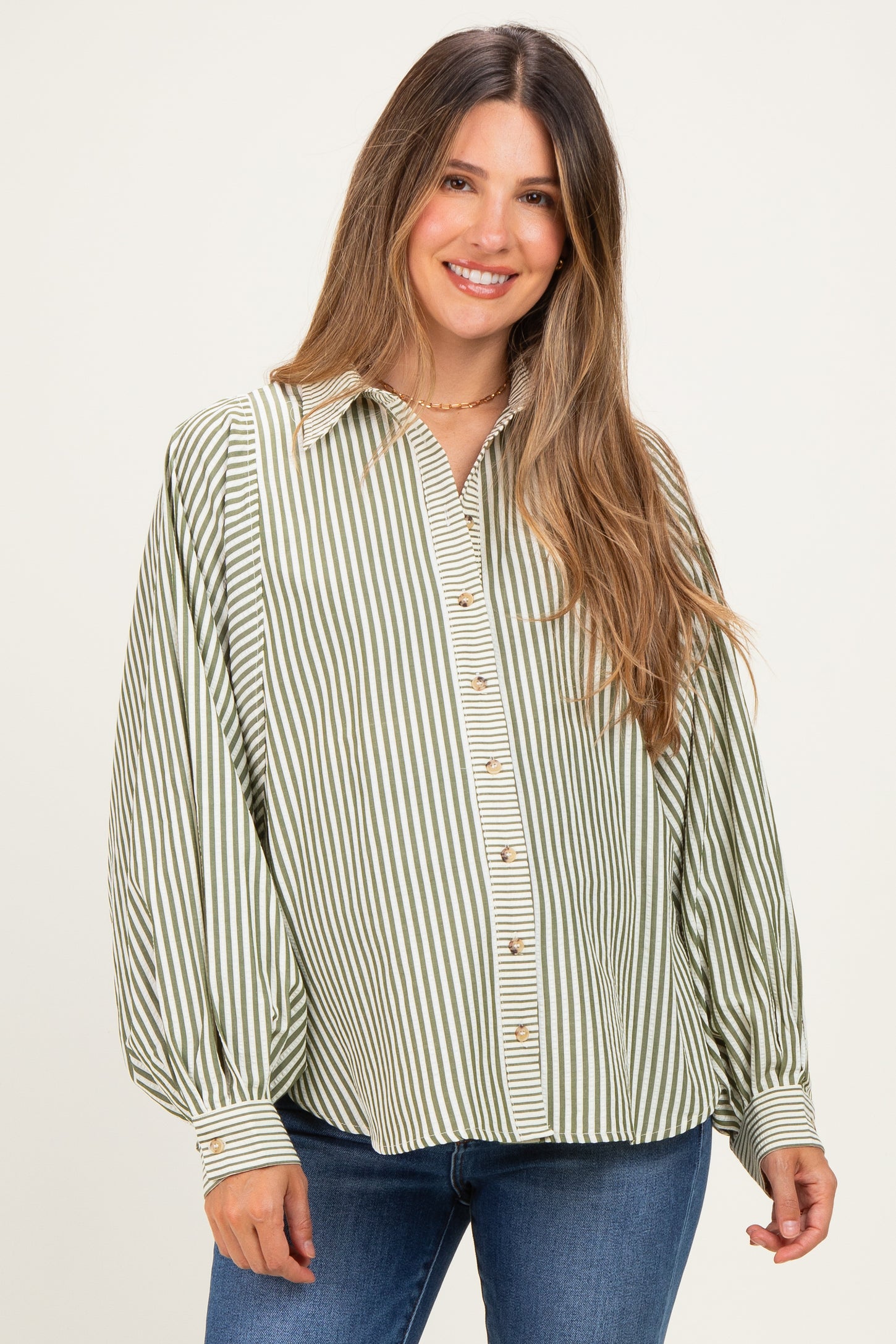 woman wearing a green and white striped maternity blouse with a button-up front and loose fit