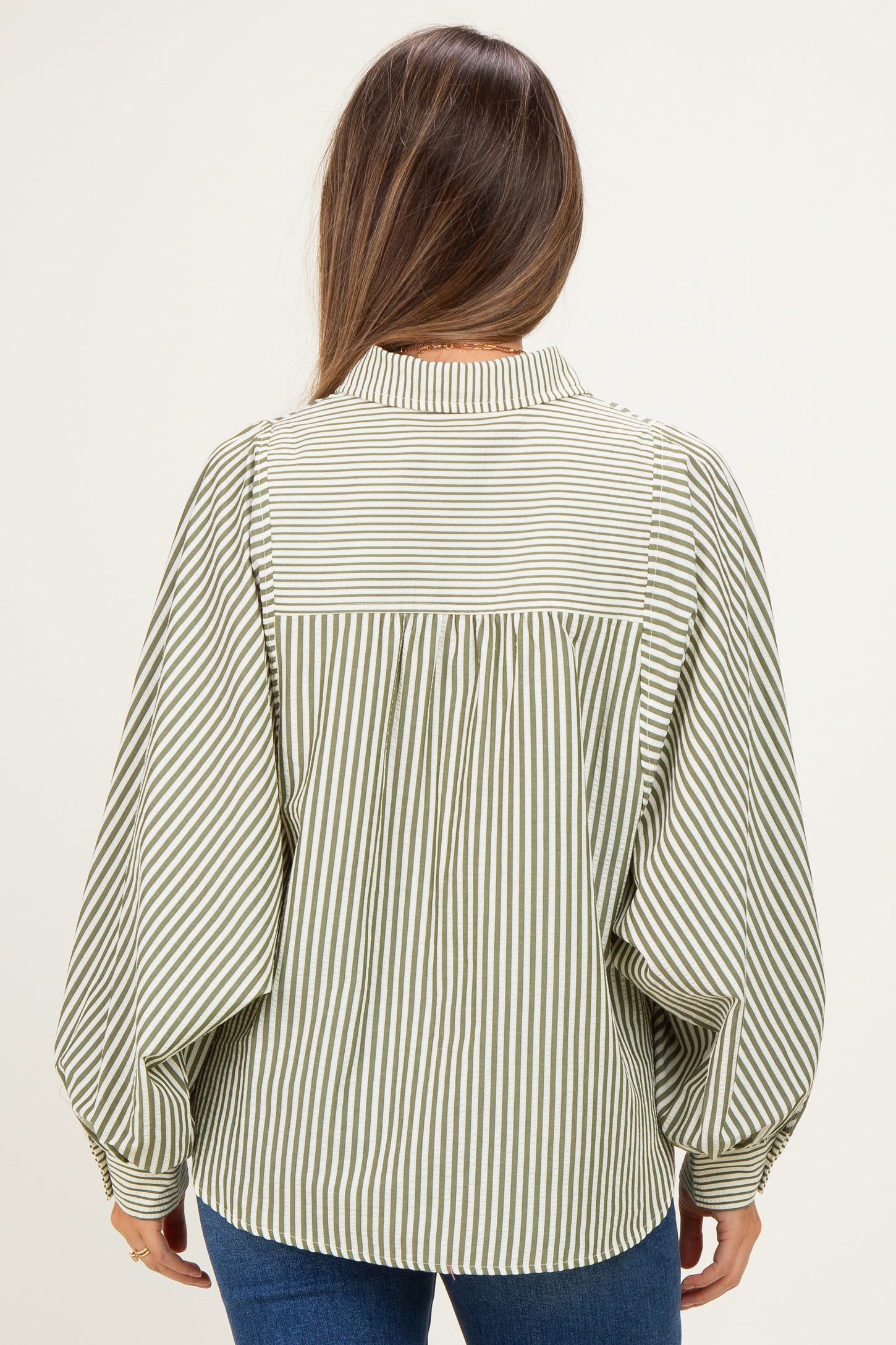 woman wearing a green and white striped maternity blouse with balloon sleeves, showing the back view