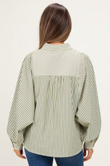 woman wearing a green and white striped maternity blouse with balloon sleeves, showing the back view