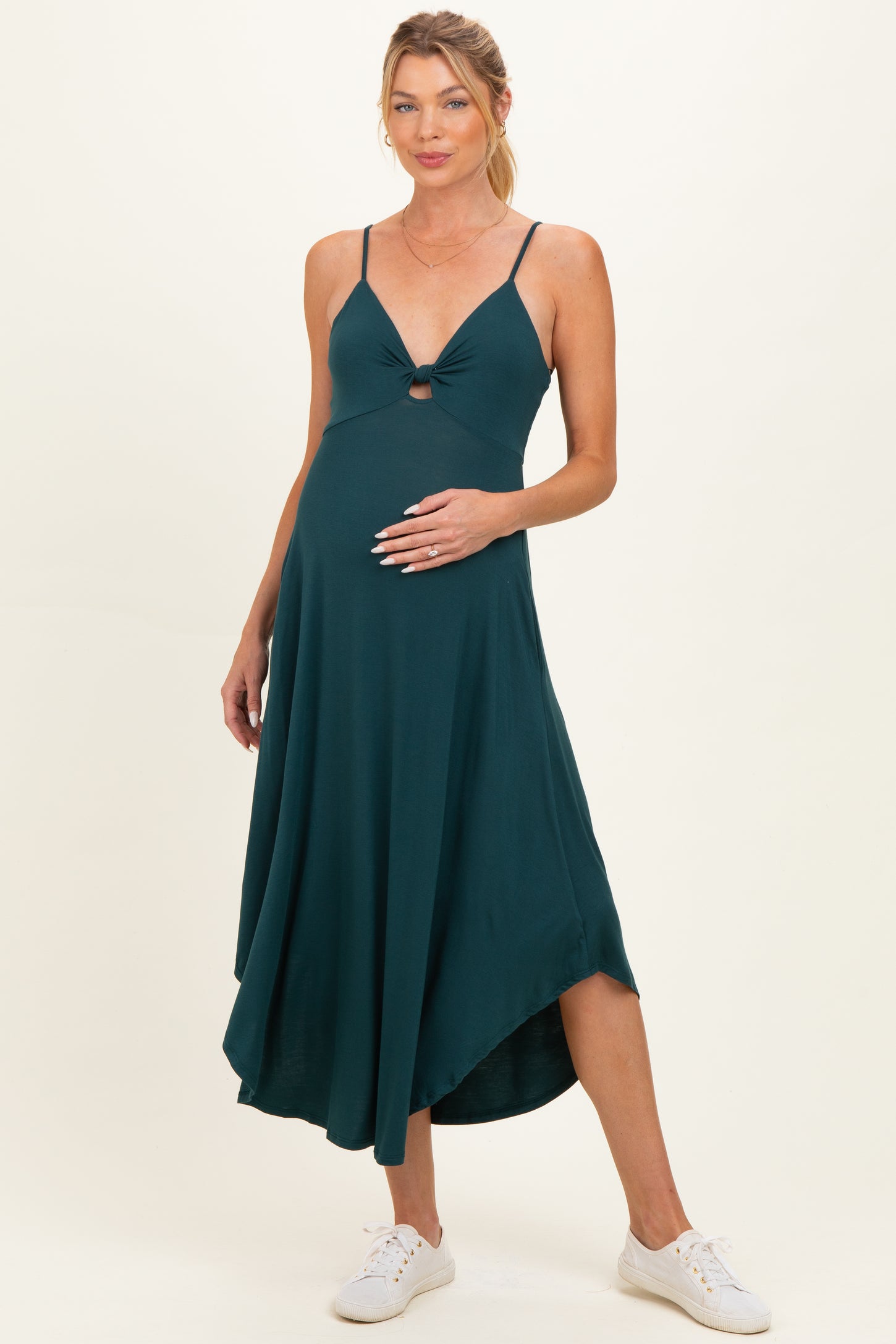 woman wearing a teal maternity dress with a front cutout and adjustable straps, highlighting her baby bump