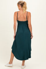 woman wearing a dark teal maternity maxi dress with adjustable straps and a flowing hem, showing her baby bump