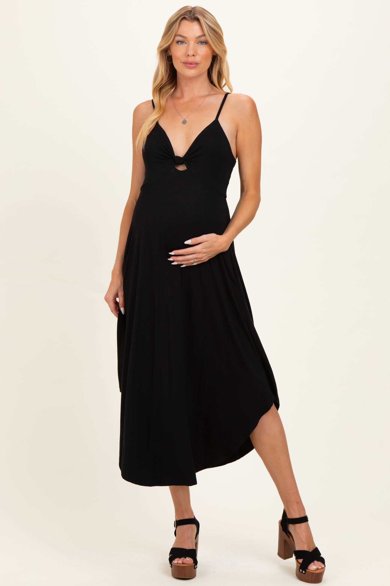 woman wearing a black maternity midi dress with a cut-out detail and holding her baby bump