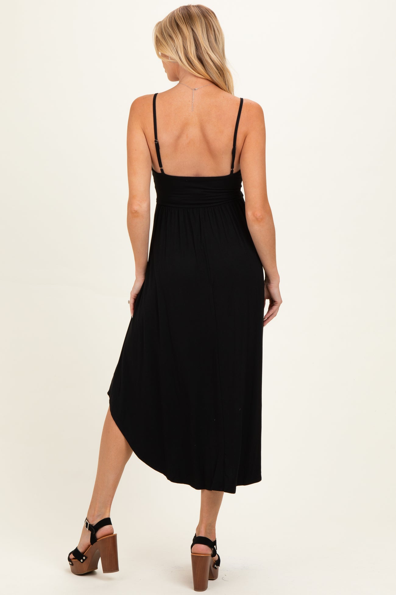 woman wearing a black maternity maxi dress with adjustable straps, showing a relaxed fit at the back