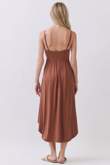 woman wearing a brown sleeveless maxi dress with a cinched waist and a flowy skirt, seen from the back